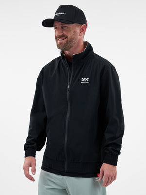 Smiling man wearing black SELKIRK zip jacket with chest logo and matching SELKIRK cap