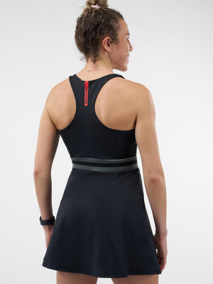Woman shown from behind wearing black racerback athletic dress with gray-striped waistband and red logo tab at upper back.