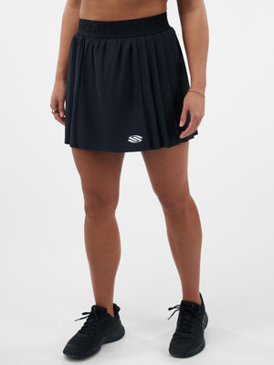 Black pleated athletic skort with small white S logo at front hem, modeled on cropped torso and legs.