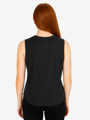 Rear view of red-haired woman wearing a black sleeveless tank top and black leggings