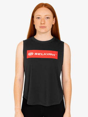 Young woman wearing a black sleeveless top with a red rectangular SELKIRK logo centered on the chest.