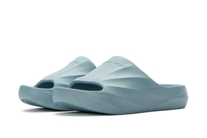 Light blue molded slide sandals with contoured footbed and textured sole on white background.