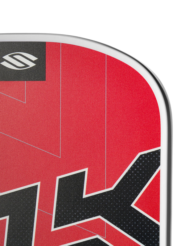 Close-up of a red paddleboard corner showing a stylized S logo and bold black partial lettering on textured surface.